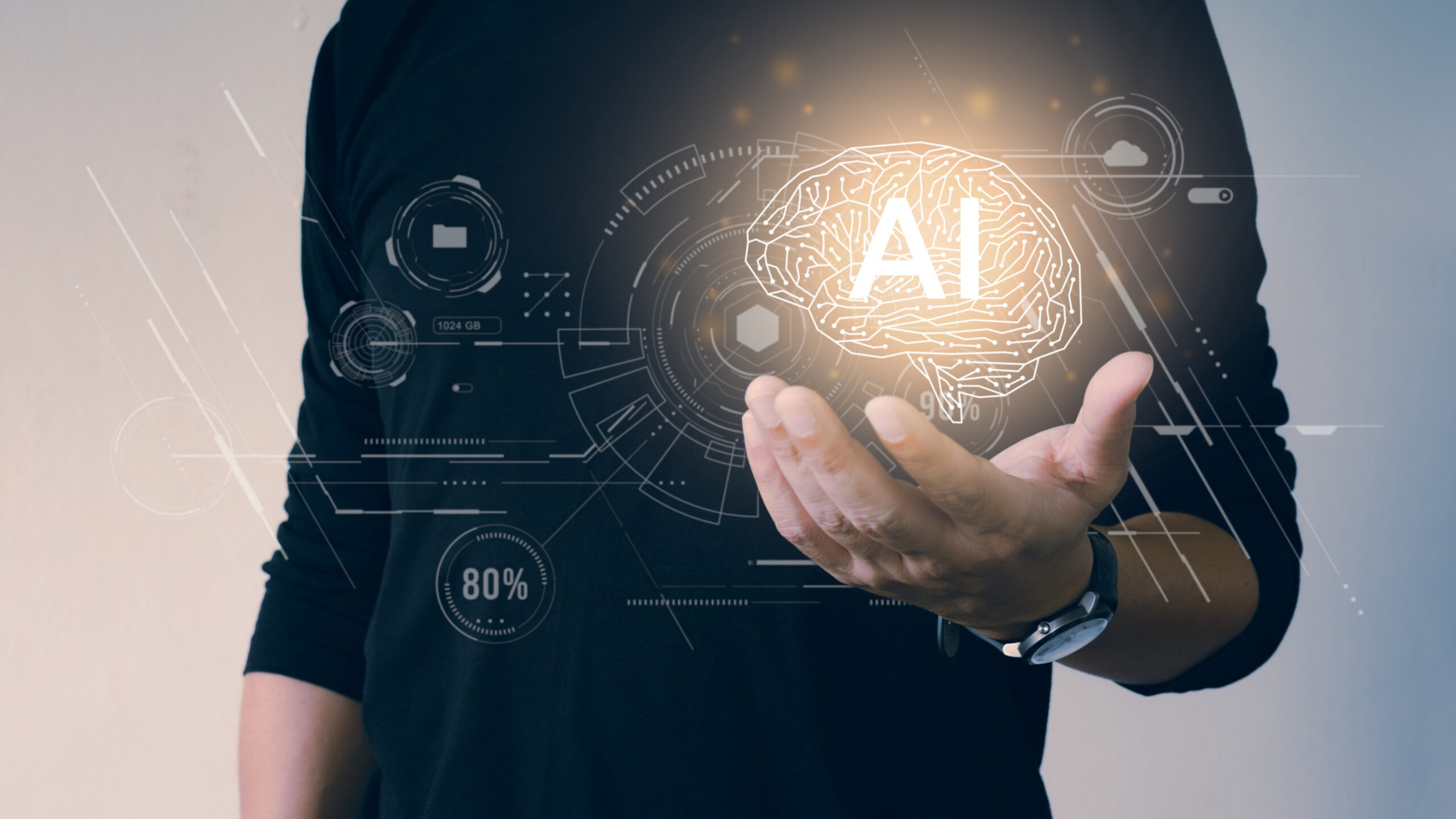 A person in a black long-sleeve shirt is holding out a hand, with a glowing brain icon labeled 'AI' hovering above the palm. Surrounding the brain icon are various digital interface elements, including circular graphs and data indicators. One of the circular graphs shows '80%'. The image visually represents artificial intelligence and its integration with human interaction, highlighting technological advancements and innovation in AI.
